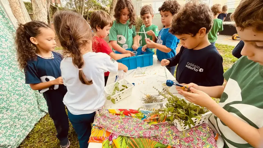 Criança pequena brincando com folhas na área verde do campus